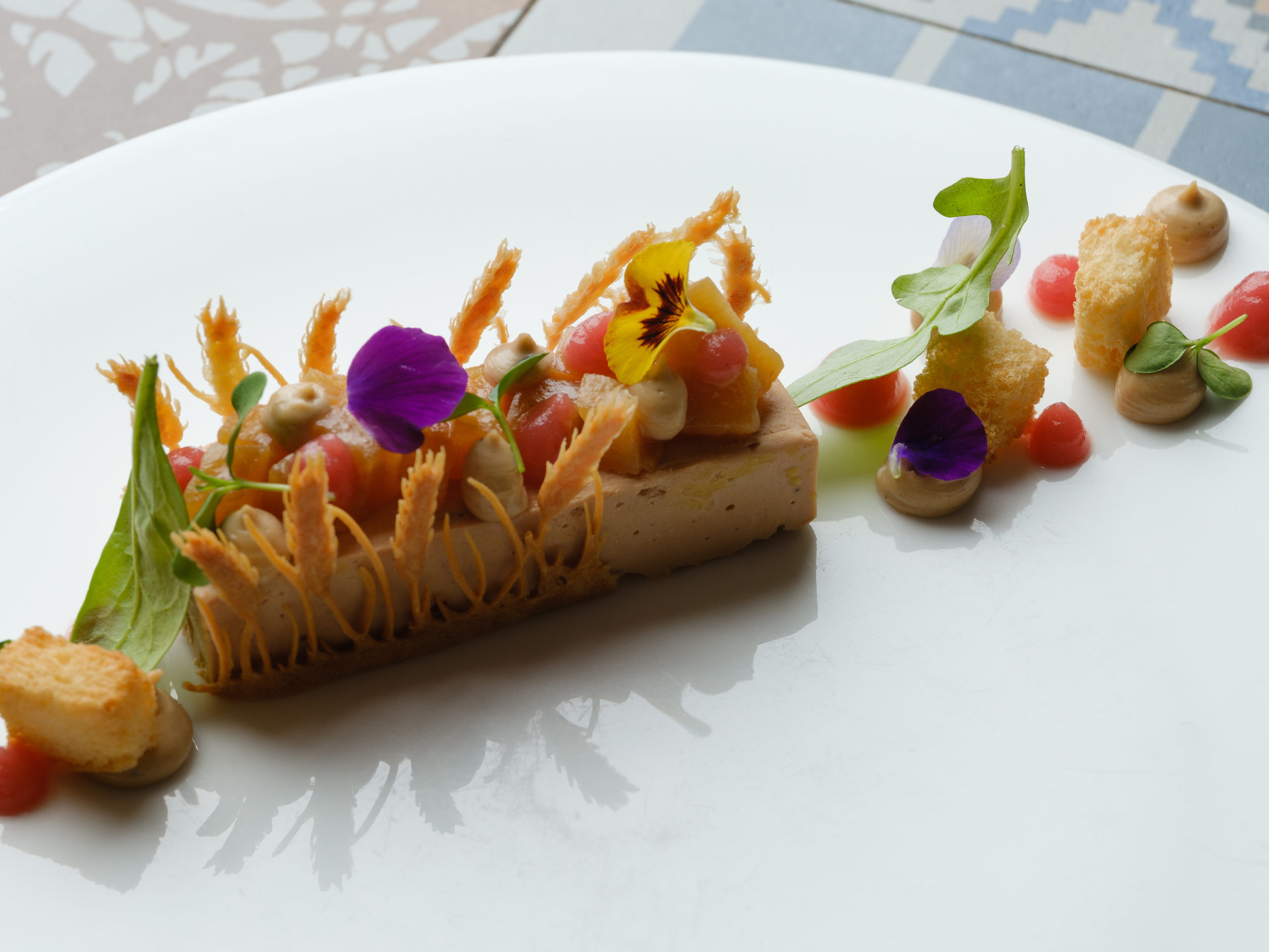 Terrine de foie gras parfumée au Passito di Trani, servie avec pain brioché, poires caramélisées, chutney pommes-framboises et éclats de noisettes – création gastronomique du restaurant La Dispensa à Neuchâtel.