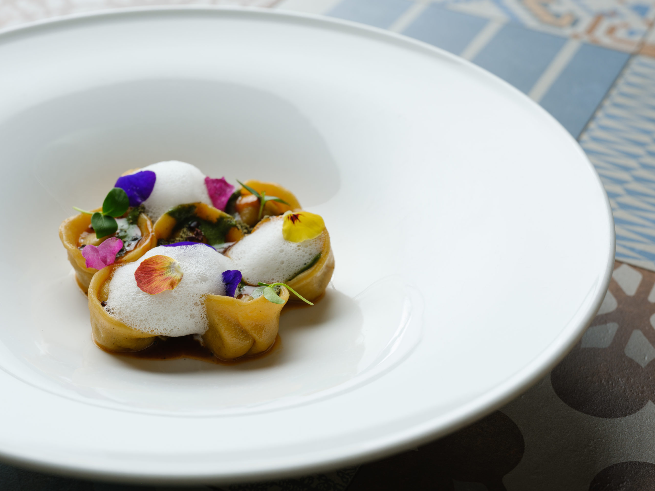 Cappelletti au sanglier, crème de sauge et genièvre, décorés de fleurs comestibles – création gastronomique italienne contemporaine du restaurant La Dispensa à Neuchâtel.