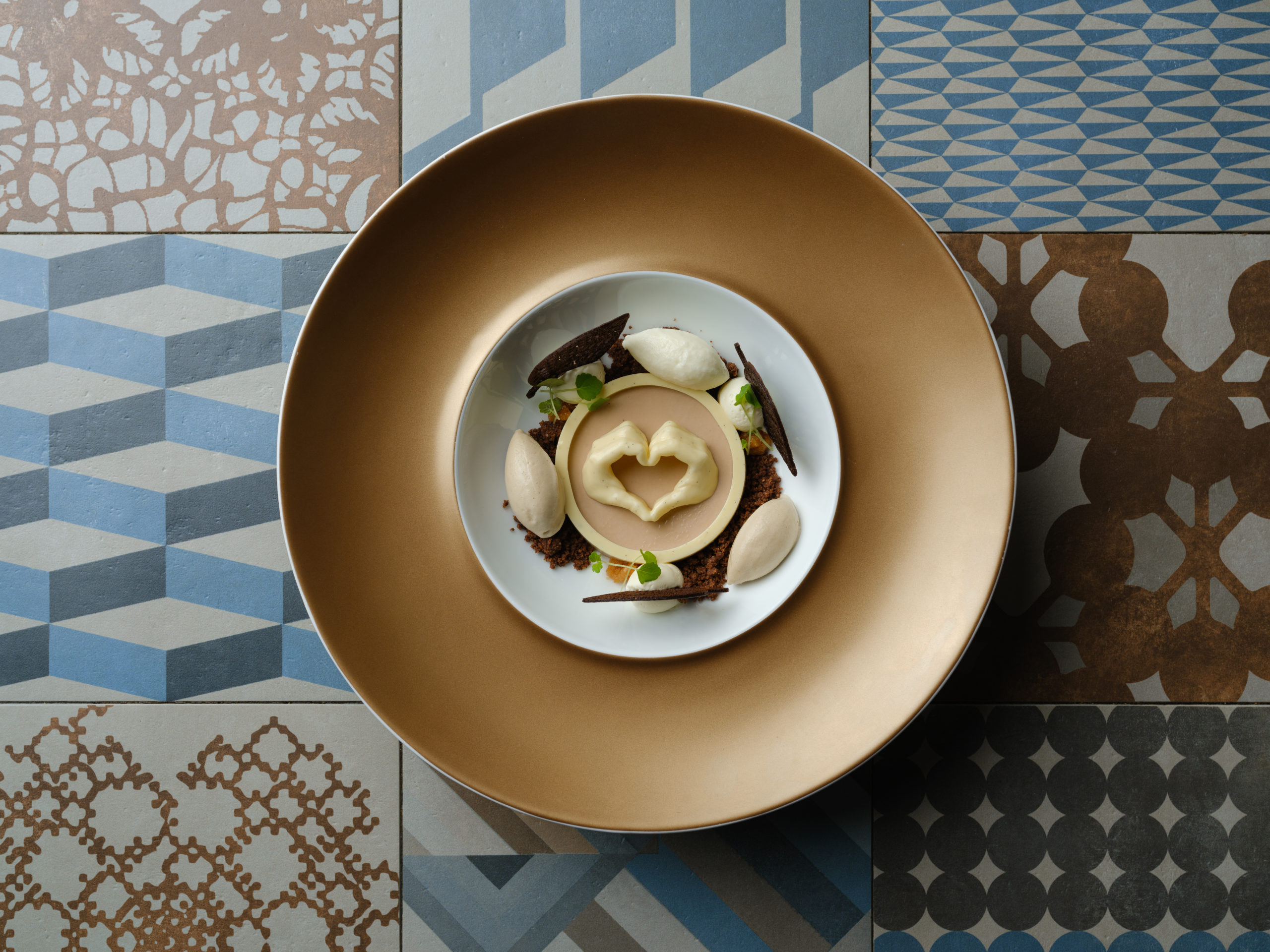 Dessert gastronomique du restaurant La Dispensa à Neuchâtel : Tiramisù mon amour, bavarois café et chocolat, praliné à l’amaretto, glace mascarpone et café, dressage raffiné sur assiette dorée.